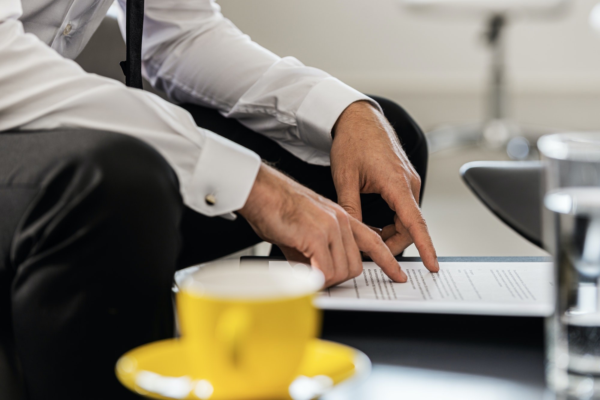 Businessman sitting at an office coffee table proofreading a document